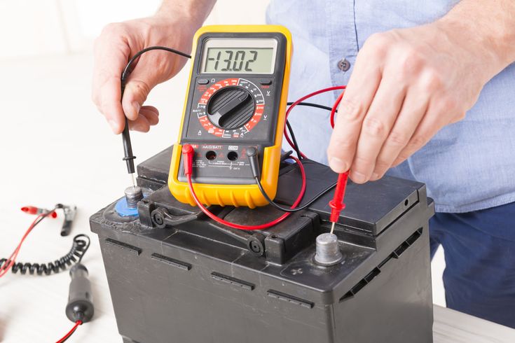 Multimeter testing electrical connections in a car's fuse box to diagnose parasitic drain