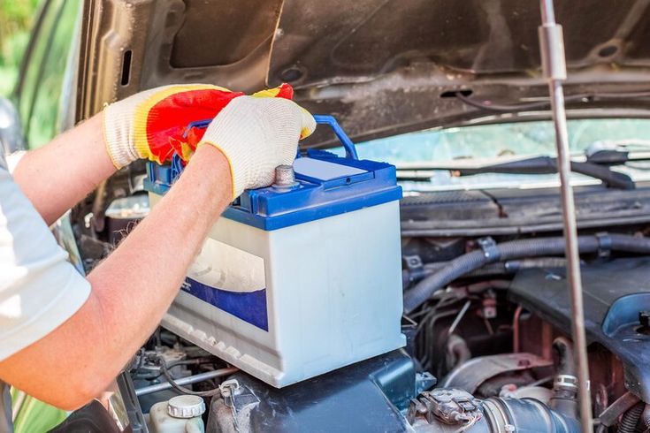 Multimeter testing a car's fuse box and electrical connections under the hood